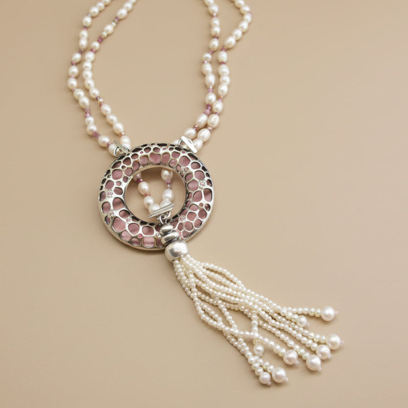 Pearl necklace with a silver circular pendant on a beige background